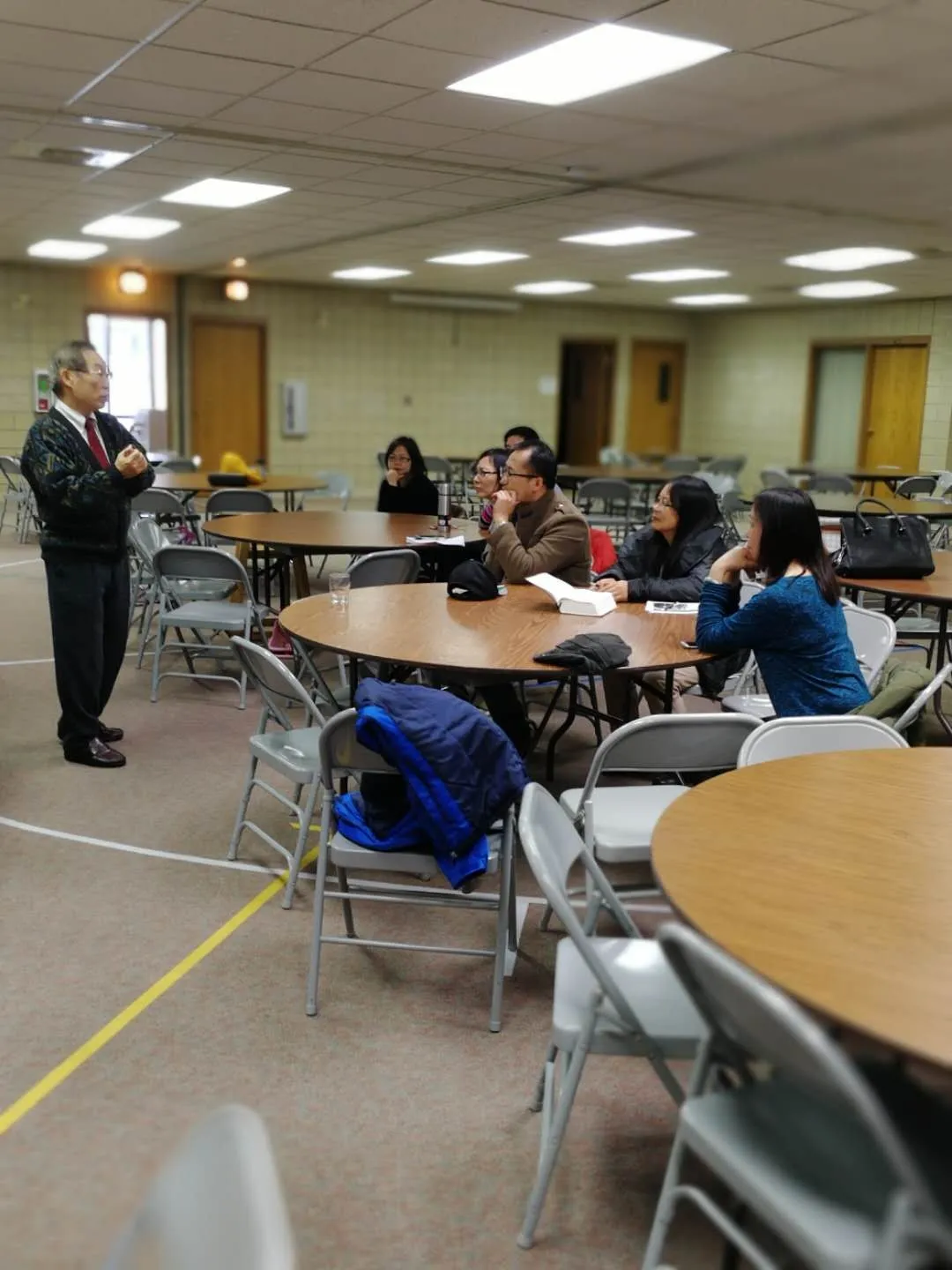 Pastor Tsu-Kung Chuang talking with a small group seated at round tables